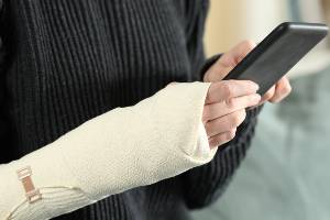 person with arm injury holding smartphone