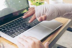 worker with injured hand on laptop