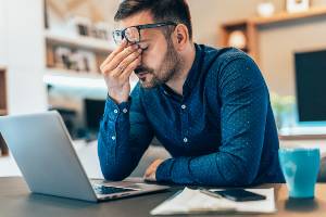 worker rubbing nose at desk