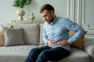 man grabbing stomach in pain