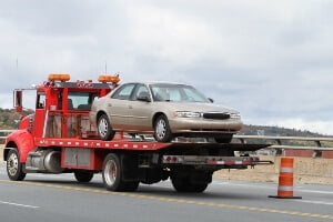 Stock image of a tow truck carrying a car on a highway