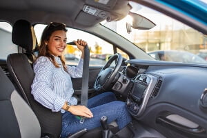 young woman fastening her seat belt before beginning to drive