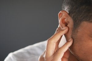 man holding ear in pain