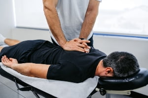 Chiropractor adjusting client back.