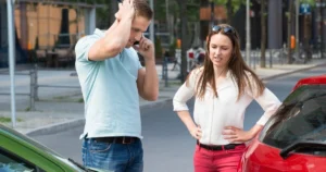 Two people stressed over a car accident with one on the phone.