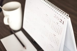 desk with calendar in front of notepad and coffee mug